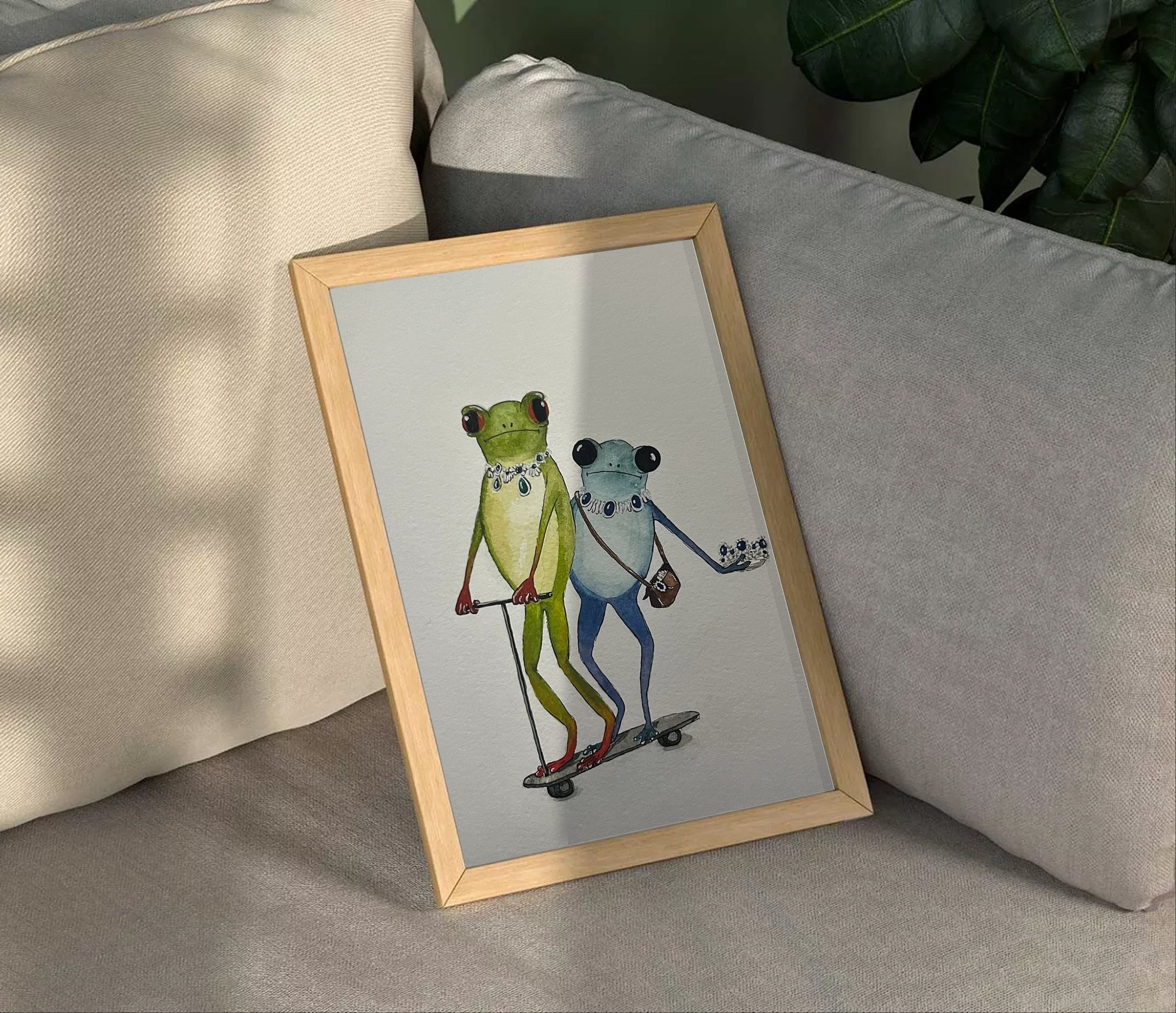 Framed artwork of two frogs on a skateboard on a couch
